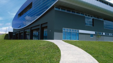 Exterior view of grey concrete clad stadium building architecture, building, corporate headquarters, daytime, facade, grass, headquarters, house, real estate, sky, structure, teal