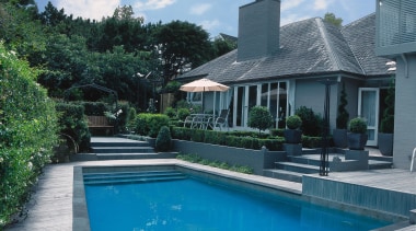 Outdoor pool and patio area featuring grey paving backyard, cottage, estate, home, house, leisure, outdoor structure, property, real estate, residential area, resort, roof, sky, swimming pool, villa, water, teal