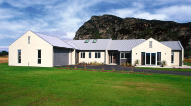 Exterior view of entire cream clad house with architecture, barn, cloud, cottage, estate, facade, farm, farmhouse, field, grass, grassland, home, house, land lot, landscape, lawn, pasture, property, real estate, residential area, roof, rural area, siding, sky, teal, green