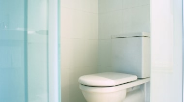 View of white toilet in small room. - bathroom, bathroom accessory, bathroom cabinet, bathroom sink, bidet, ceramic, plumbing fixture, product design, tap, tile, toilet, toilet seat, white