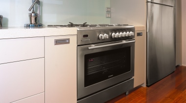 A view of a kitchen area, wooden flooring, cabinetry, countertop, gas stove, home appliance, kitchen, kitchen appliance, kitchen stove, major appliance, microwave oven, oven, small appliance, white