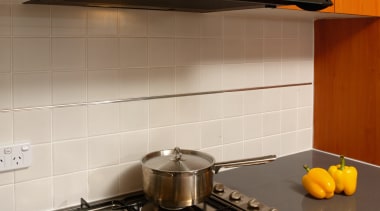 A view of a kitchen, wooden cabinetry, grey countertop, floor, flooring, gas stove, home appliance, kitchen, kitchen appliance, kitchen stove, room, tile, under cabinet lighting, brown, gray
