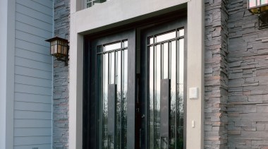 Exterior view of apartment entranceway showing glass and door, facade, home, house, porch, real estate, sash window, siding, window, gray, black