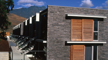 Exterior view of apartments showing stone cladding, timber architecture, building, elevation, facade, home, house, property, real estate, residential area, roof, siding, sky, window, black, blue