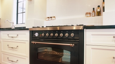 View of black oven set in cream kitchen cabinetry, countertop, cuisine classique, floor, flooring, home appliance, interior design, kitchen, kitchen appliance, kitchen stove, major appliance, oven, room, white