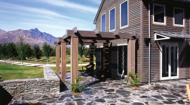 An exterior view of patio with stone pavers, backyard, cottage, elevation, estate, facade, home, house, landscape, outdoor structure, property, real estate, residential area, siding, sky, walkway, window, blue