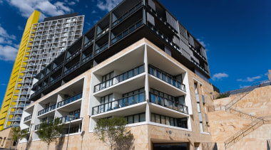 An exterior view of the apartments. - An apartment, architecture, building, commercial building, condominium, corporate headquarters, elevation, facade, home, mixed use, property, real estate, residential area, blue