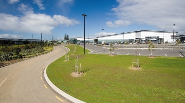 A view of the building and man made asphalt, cloud, grass, infrastructure, race track, road, sky, sport venue, structure, tree, gray