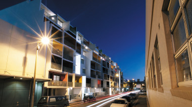 Exterior view of this new apartment development featuring apartment, architecture, building, car, city, commercial building, condominium, downtown, evening, facade, infrastructure, lighting, metropolis, metropolitan area, mixed use, neighbourhood, night, real estate, residential area, road, sky, street, town, urban area, blue