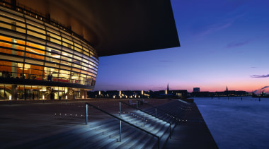 An exteior view of the building. - An architecture, atmosphere, building, city, cityscape, convention center, corporate headquarters, dawn, dusk, evening, headquarters, horizon, landmark, metropolis, metropolitan area, night, opera house, performing arts center, reflection, sky, structure, sunlight, sunset, water, blue, black