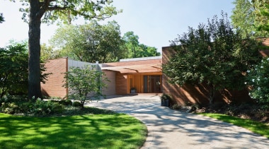 An exterior view of the entrance way to backyard, cottage, courtyard, estate, facade, garden, grass, home, house, landscape, landscaping, outdoor structure, property, real estate, residential area, tree, villa, walkway, yard, white, green