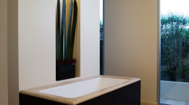 The tub fills from a ceiling-mounted pourer and floor, furniture, interior design, room, table, brown, gray