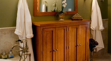 A view of this bathroom features a steam bathroom, cabinetry, chest of drawers, floor, flooring, furniture, home, interior design, room, brown