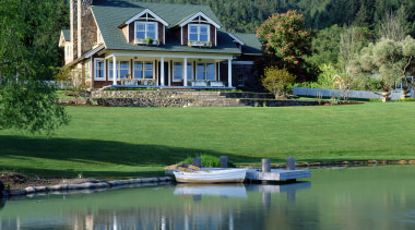 An exterior view of this traditional masonry home bank, canal, cottage, estate, farmhouse, home, house, lake, landscape, pond, property, real estate, reflection, reservoir, tree, water, waterway, green