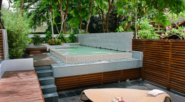 A view of this outdoor entertainment area featuring backyard, furniture, leisure, outdoor furniture, outdoor structure, patio, property, real estate, resort, sunlounger, swimming pool, table, wood, yard, green, gray