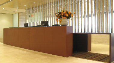 The leather and wenge veneer reception desk reflects floor, flooring, furniture, hardwood, interior design, lobby, wall, orange, brown