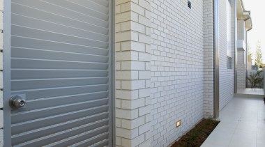 Side view of brick house, alongside steel gate apartment, architecture, daylighting, door, facade, home, house, interior design, property, real estate, wall, window, gray