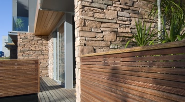 A solid stone wall with wood fencing - architecture, deck, facade, hardwood, home, house, lumber, outdoor structure, real estate, siding, wall, wood, wood flooring, wood stain, brown