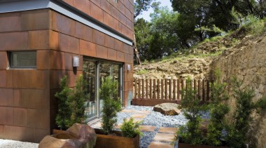 Exerior view of bathroom featuring sliding doors, pavers, backyard, courtyard, estate, home, house, landscape, landscaping, outdoor structure, property, real estate, yard, brown
