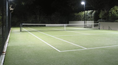 Image of a residential tennis court which was artificial turf, ball game, grass, net, plant, racquet sport, real tennis, sport venue, sports, structure, tennis, tennis court, green, black