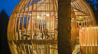 Image of the Yellow Treehouse restaurant which has architecture, landmark, light, lighting, night, reflection, sky, structure, tourist attraction, wood, brown, orange