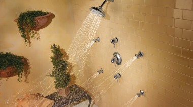 view of shower enclosure which features the showerheads fauna, tile, wall, orange, brown