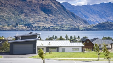 Exterior view of a home which features solar alps, cottage, elevation, estate, fjord, highland, home, house, lake, landscape, mountain, mountain range, property, real estate, residential area, roof, sky, suburb, tree, white