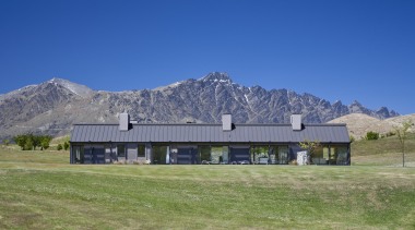 Exterior view of a country home which features alps, barn, cottage, elevation, estate, farm, farmhouse, field, grass, grassland, highland, home, house, hut, land lot, landscape, meadow, mount scenery, mountain, mountain range, mountainous landforms, national park, pasture, property, ranch, real estate, roof, rural area, sky, blue