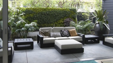 View of outdoor living space filled with mature floor, furniture, house, interior design, living room, outdoor structure, patio, property, real estate, gray