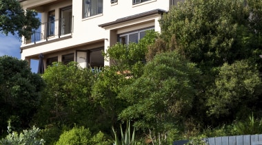 Exterior view of a home with Italian aesthetic apartment, architecture, building, cottage, estate, facade, home, house, landscaping, neighbourhood, outdoor structure, plant, property, real estate, residential area, roof, sky, suburb, tree, villa, window, brown