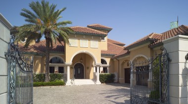 Exterior view of an Italian villa-styled waterfront home. arecales, building, estate, facade, hacienda, home, house, mansion, palm tree, property, real estate, residential area, villa, gray, teal