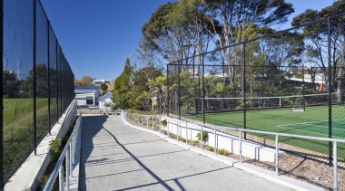 Exterior view of a concrete pathway at Albany architecture, area, estate, fence, grass, house, landscape, outdoor structure, park, plant, public space, real estate, recreation, residential area, sky, sport venue, structure, tree, walkway, white