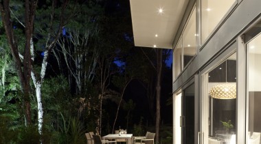 Nighttime shot of contemporary home surrounded by trees. architecture, daylighting, deck, home, house, interior design, outdoor structure, patio, real estate, black, orange