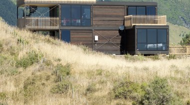 View of contemporary home on tussocky slope. - architecture, home, house, land lot, landscape, prairie, property, real estate, rural area, shack, shed, sky, orange
