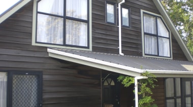 View of brown timber house with square windows. cottage, facade, home, house, porch, property, real estate, roof, siding, window, black, gray