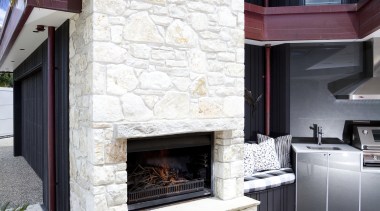 View of contemporary outdoor stone fireplace with table fireplace, hearth, home, house, interior design, living room, wall, window, white