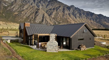 Exterior view of house with dark walls and cottage, elevation, farmhouse, home, house, hut, landscape, log cabin, mountain, mountain range, property, real estate, roof, siding, brown, gray