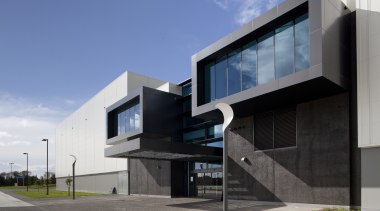 Exterior with dark grey cladding. - Exterior with architecture, building, commercial building, corporate headquarters, elevation, facade, headquarters, home, house, real estate, residential area, teal, gray, black
