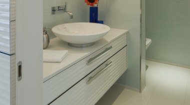 A powder room sits behind one of the bathroom, bathroom accessory, bathroom cabinet, bathroom sink, floor, interior design, plumbing fixture, product design, room, sink, tap, tile, gray