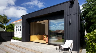 A deep soffit provides some shade on the architecture, backyard, cottage, facade, home, house, real estate, shed, siding, black, gray