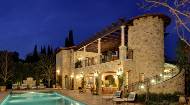 The rustic guest house includes a balcony, covered architecture, building, estate, evening, hacienda, home, hotel, house, landscape lighting, lighting, mansion, night, property, real estate, reflection, sky, villa, blue, brown