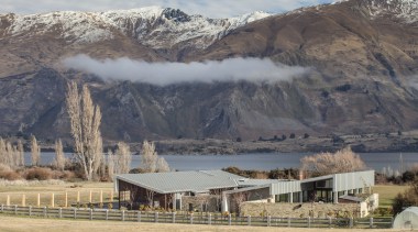 This large contemporary courtyard house nestles into the alps, cloud, elevation, fell, highland, hill, landscape, mountain, mountain range, mountainous landforms, national park, ranch, rural area, sky, snow, tree, wilderness, winter, gray