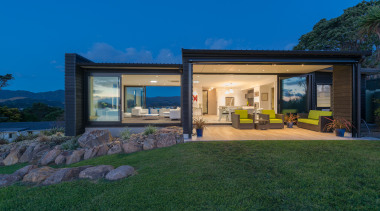 A large overhang creates a sheltered outdoor living architecture, backyard, cottage, estate, facade, home, house, landscape, property, real estate, sky, villa, window, yard, blue