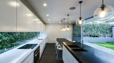 Parallel cabinets reinforce the strong horizontality of this architecture, ceiling, countertop, daylighting, house, interior design, kitchen, lighting, real estate, gray