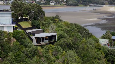 Hidden from the street above, the holiday home home, house, property, real estate, residential area, suburb, tree, water, brown, gray