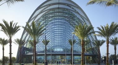 The new ARTIC transit hub in Anaheim is architecture, arecales, building, city, condominium, corporate headquarters, hotel, metropolitan area, mixed use, palm tree, plant, sky, tree, teal