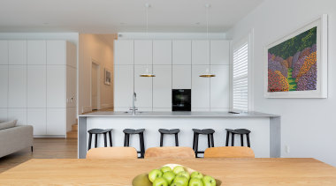 A wall of floor-to-near-ceiling minimalist white cabinetry conceals gray