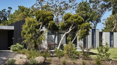 A high, solid, charred-timber wall shields the home 
