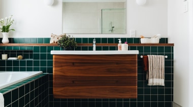 Evergreen tiles and a walnut-clad cantilevered vanity make 