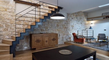 View of the living room and staircase from architecture, brick, building, ceiling, countertop, floor, flooring, furniture, hardwood, home, house, interior design, living room, loft, property, real estate, room, stairs, stone wall, table, wall, wood, gray
